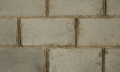 Wall of large, blocky gray bricks with sloppy cement joints. Texture closeup.
