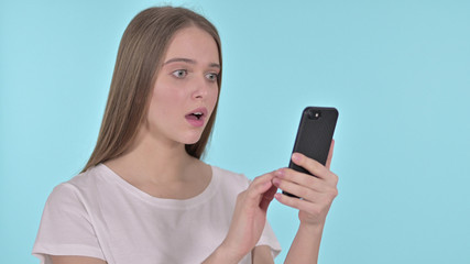 Young Woman Upset by Loss on Smartphone, Blue Background