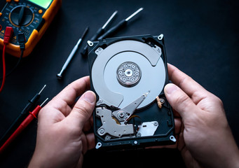 Man hands with screwdrivers and digital mutimeter fixing hard drive