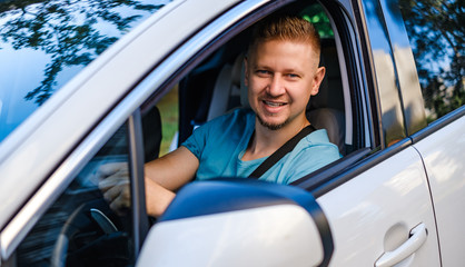 Young attractive man in white car, lookind at the camera