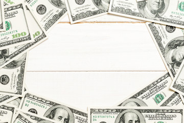 Frame made of dollars with copy space in the middle. Top view of business concept on white wooden background with copy space