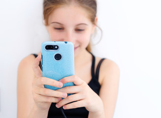 Teenage girl with blue smartphone in white room