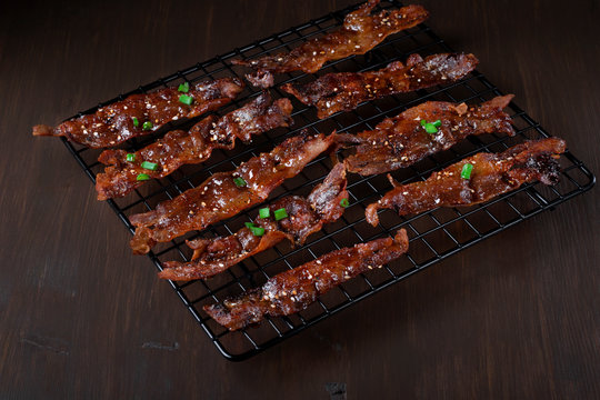Roasted bacon in sweet maple syrup glazing topped with sesame seeds and herbs on the black lattice