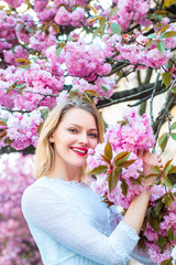 Fototapeta premium Womens day, 8 march. Beautiful woman with blooming Sakura tree and sunny day.