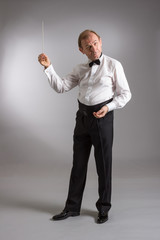 Portrait of the orchestra conductor emotionally gesticulating on a light background.
