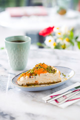 Slice of cheesecake topped with apricot sprinkled with pistachio and coffee