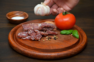  sausage and vegetables on a wooden board and hand