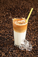 Splash of ice latte coffee drink on a brown background with coffee beans