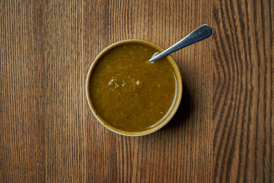 Classical Georgian cuisine sauce - Tkemali with spices in a ceramic bowl on a wooden background