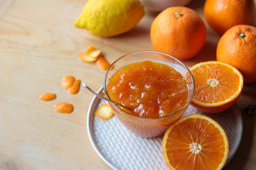 orange marmalade in a glass bowl and fresh oranges