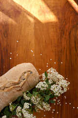 Ciabatta with olives. Fresh Italian homemade bread and spiraea flowers on the mahogany table.