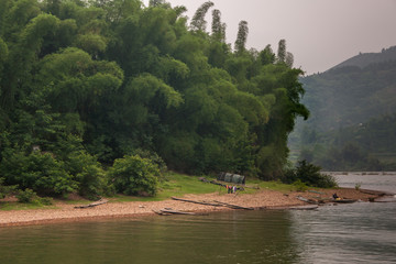 Guilin, China - May 10, 2010: Along Li River. Encampment and drying laundry on brown stone shore in...