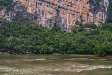 Guilin, China - May 10, 2010: Along Li River. Closeup of brown-black wall of cliff of karst...