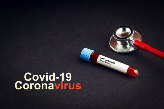 COVID-19 CORONAVIRUS text with stethoscope and blood sample vacuum tube on black background. Covid or Coronavirus Concept