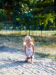 Adorable child in white dress posing outdoors.Girl having fun. Little baby girl in the park. Summer or spring vacation