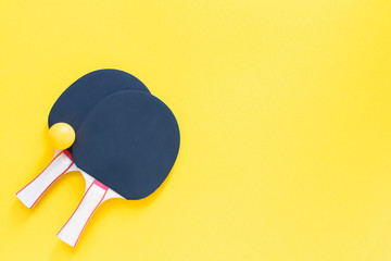 Black tennis ping pong rackets and orange balls isolated on a yellow background, sport equipment for table tennis
