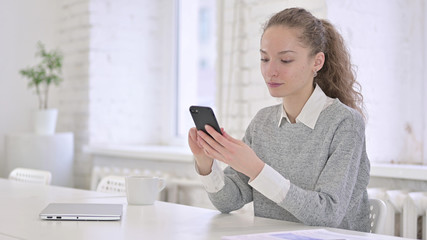 Relaxed Young Latin Woman using Smartphone in Modern Office