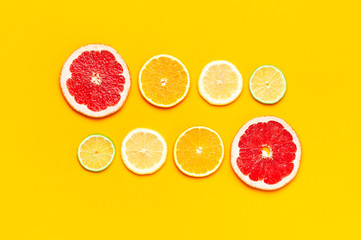 Flat lay composition with slices of fresh lemon orange grapefruit lime on yellow background top view copy space. Citrus Juice Concept, Vitamin C, Fruits. Creative summer background