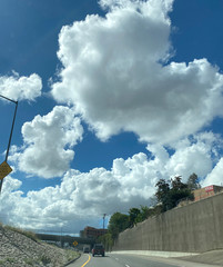 Large fluffy hang clouds over  highway