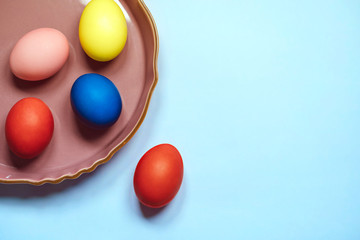 colorful eggs in plate on blue background; easter celebration concept.