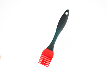 Single plastic red silicon kitchen brush close up shot isolated on pure white