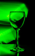empty wine glass on black background with green light