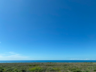 Fototapeta na wymiar Large blue sky over looms over a strip of the ocean