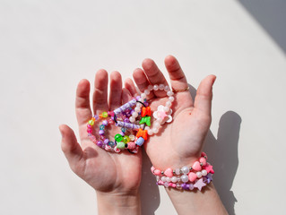 bead bracelets. beads in the hands. decorations. bijouterie. hobbies of girls. rings. background