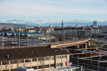 High vantage point view of industrial are of Zurich city Switzerland railroads and Swiss alps in the background