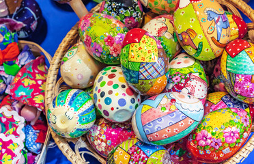 Wooden Easter eggs with bright drawings lie in a wicker basket.
