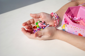 bead bracelets. casket with beads in hands. decorations. bijouterie. hobbies of girls. rings. background