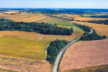 Aerial view of a country road amid fields against blue clear sky
