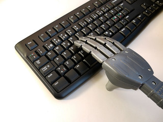 Hand of a robot working on a pc keyboard.