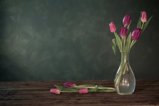 purple tulips in glass vase on wooden table