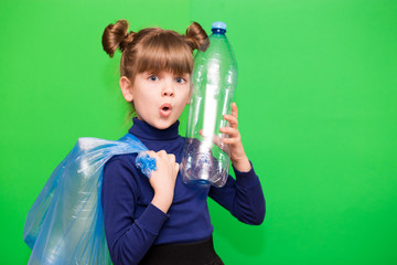 Girl hold trash bag and plastic bottle and shows interest in environmental issues isolated on green background. Child accustomed to bear responsibility for garbage since childhood.