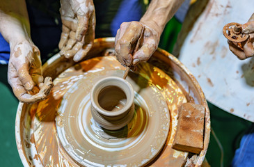 Professional potter makes a pot on a pottery wheel and teaches a pupil. Hands of a potter.