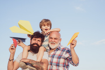 Portrait of happy father giving son piggyback ride on his shoulders and looking up. Male multi...