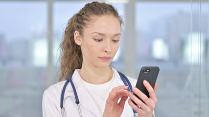 Portrait of Focused Young Female Doctor using Smartphone