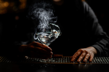woman bartender holds glass with white transparent splashing drink.