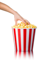 Woman hand picking popcorn from striped bucket isolated on white background
