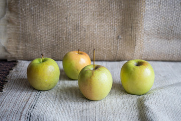Still life with green apples on the table. Apples lie on a background of drapery