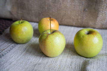 Still life with green apples on the table. Apples lie on a background of drapery