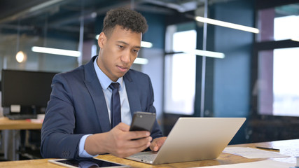 Cheerful Young Businessman using Smartphone in Office