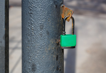 A closed lock hangs on a gate post.