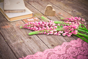Fototapeta na wymiar Wildflowers bouquet. Pink Lupine flowers and old books on rustic wooden table. Vintage floral background.