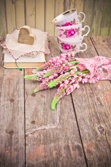 Wildflowers bouquet. Pink Lupine flowers, old books and tea cups on rustic wooden table. Vintage floral background.