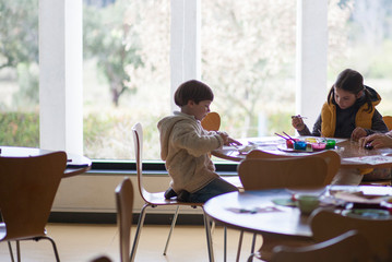 Children painting pictures at table indoors