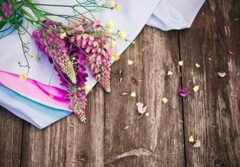 Wildflowers. Purple Lupine flowers and a silk scarf on old shabby rustic wooden table. Vintage floral background.