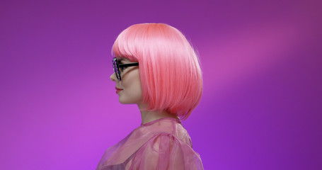 Woman with stylish pink hairstyle on purple background.