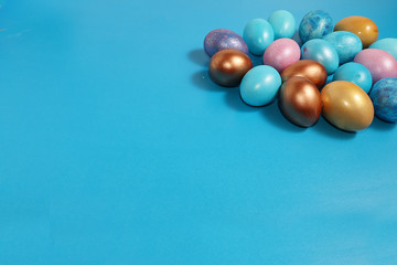 Decorated golden easter eggs on trendy blue background. Minimal holiday concept. Happy Easter background, place for text, postcard, banner for the screen.